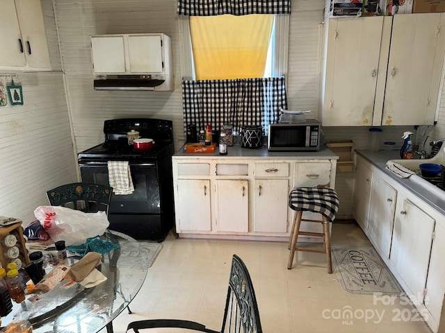 kitchen featuring wooden walls and black range with electric cooktop