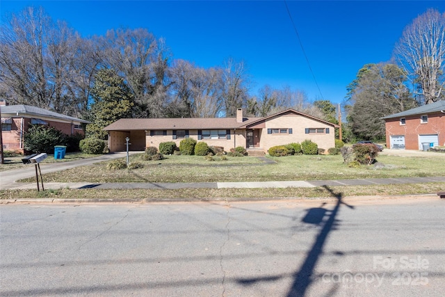 view of front of property featuring driveway, a carport, a chimney, and a front yard