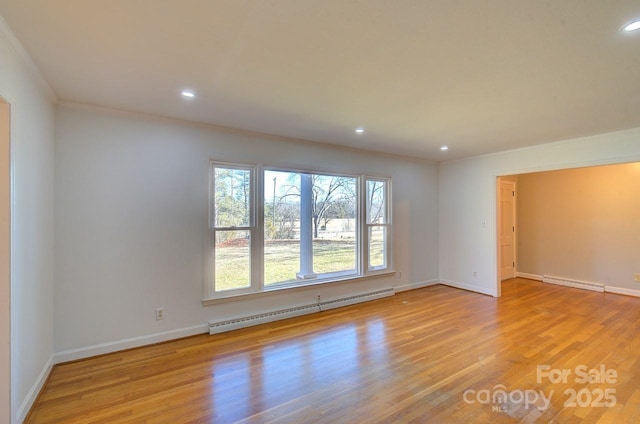 unfurnished room featuring a baseboard heating unit and light hardwood / wood-style floors