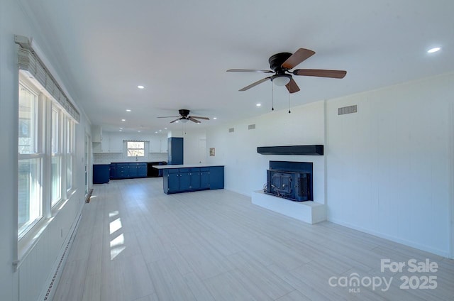 unfurnished living room with a baseboard heating unit and ceiling fan