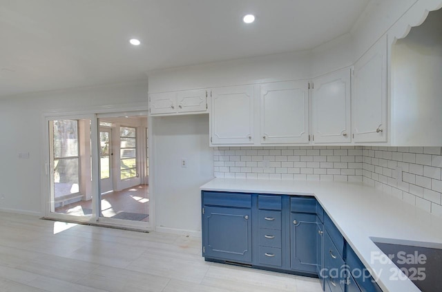 kitchen featuring decorative backsplash, white cabinets, and blue cabinets