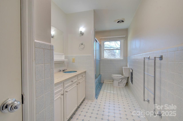 full bathroom with shower / bath combination with glass door, vanity, toilet, and tile walls