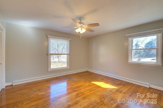 empty room featuring ceiling fan, a baseboard radiator, and wood-type flooring