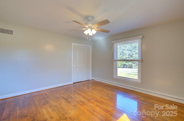 spare room with ceiling fan, hardwood / wood-style floors, and a baseboard heating unit