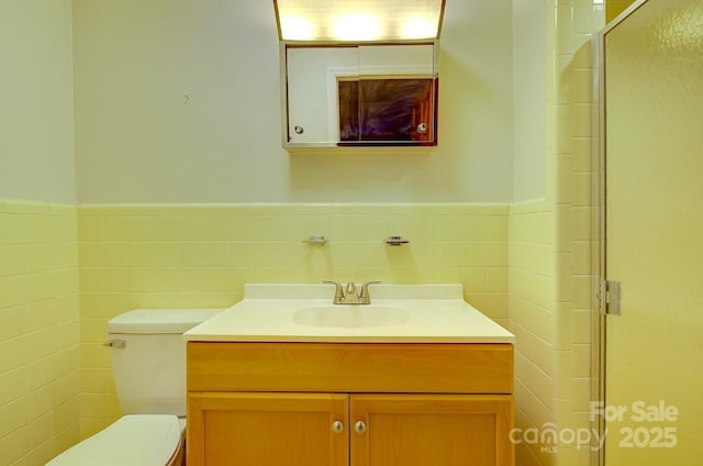 bathroom with tile walls, vanity, toilet, and walk in shower