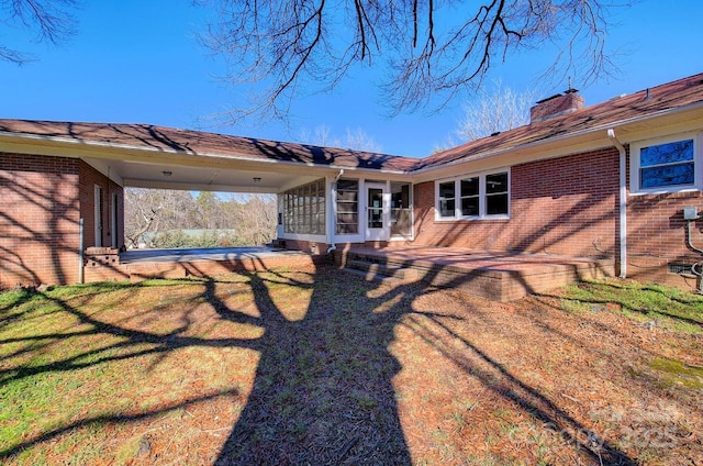 rear view of house featuring a sunroom, a patio, and a lawn