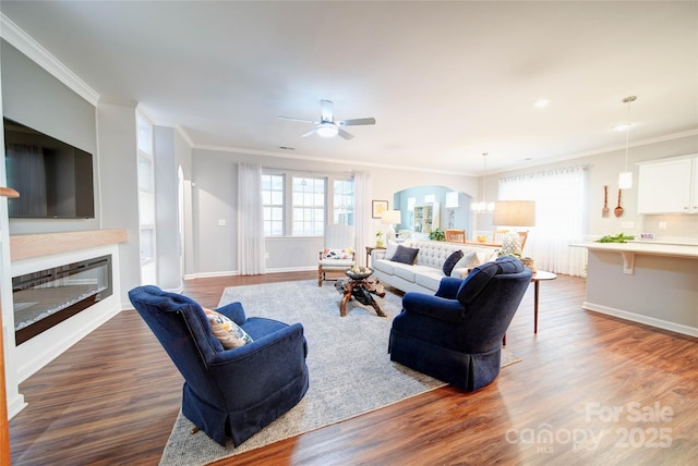 living room with dark wood-type flooring, ornamental molding, and ceiling fan