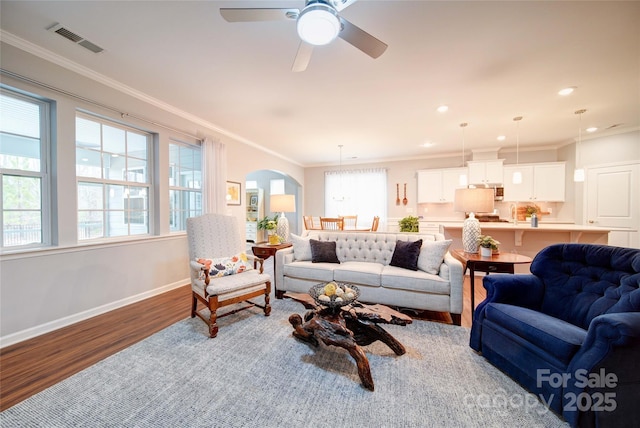 living room with hardwood / wood-style flooring, ornamental molding, and ceiling fan