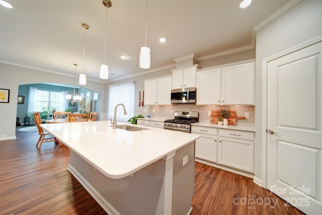 kitchen with a kitchen island with sink, sink, decorative light fixtures, and appliances with stainless steel finishes