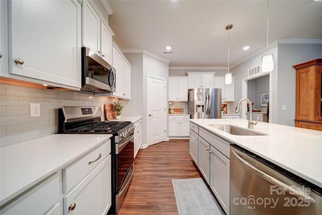 kitchen featuring appliances with stainless steel finishes, sink, white cabinets, hanging light fixtures, and crown molding