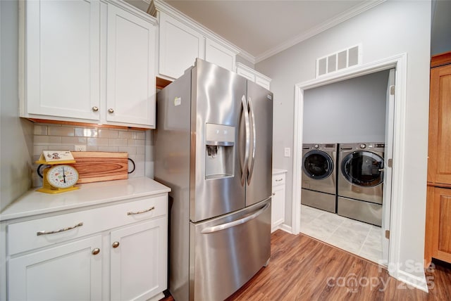 kitchen featuring white cabinets, crown molding, separate washer and dryer, and stainless steel fridge