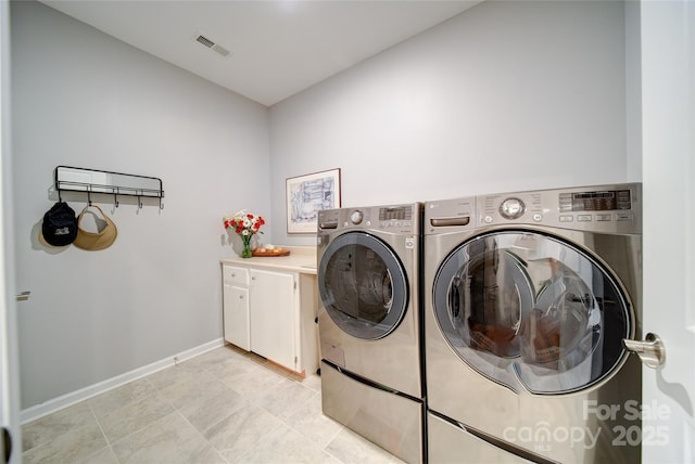 laundry area featuring washer and clothes dryer and cabinets