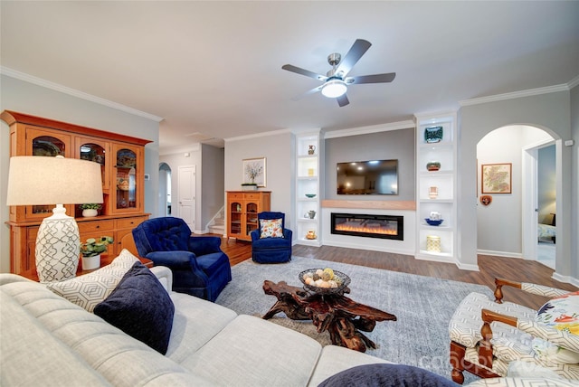 living room featuring ceiling fan, ornamental molding, built in features, and wood-type flooring