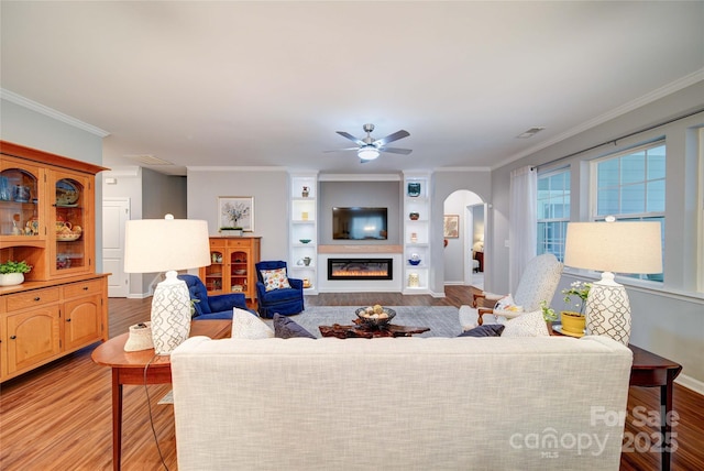 living room featuring crown molding, ceiling fan, and light wood-type flooring