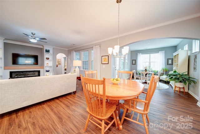 dining room with ornamental molding, wood-type flooring, and ceiling fan with notable chandelier