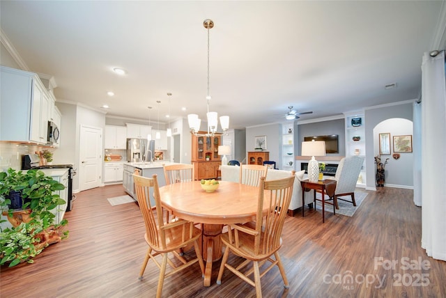 dining space with ornamental molding, dark hardwood / wood-style flooring, ceiling fan with notable chandelier, and built in features