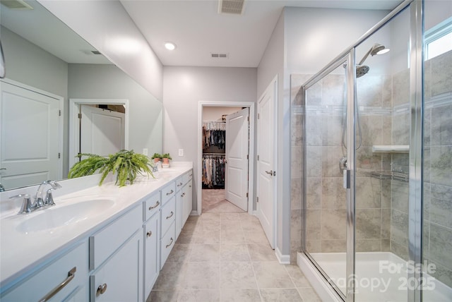 bathroom with tile patterned flooring, vanity, and walk in shower