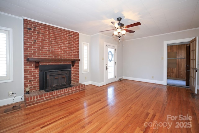 unfurnished living room with a fireplace, crown molding, wood-type flooring, and ceiling fan