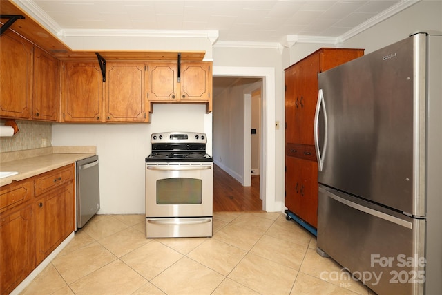 kitchen featuring light tile patterned floors, crown molding, and stainless steel appliances