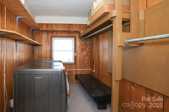 washroom with washing machine and clothes dryer, carpet floors, and wood walls