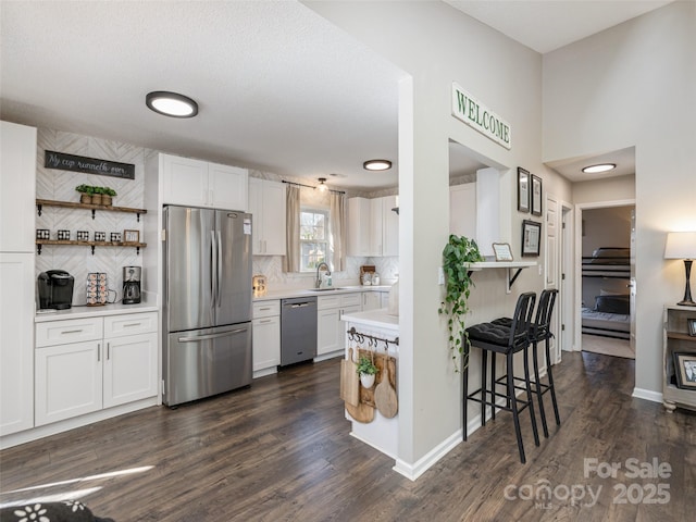 kitchen featuring sink, white cabinets, dark hardwood / wood-style flooring, backsplash, and stainless steel appliances