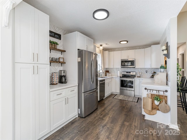 kitchen with white cabinetry, appliances with stainless steel finishes, dark wood-type flooring, and backsplash