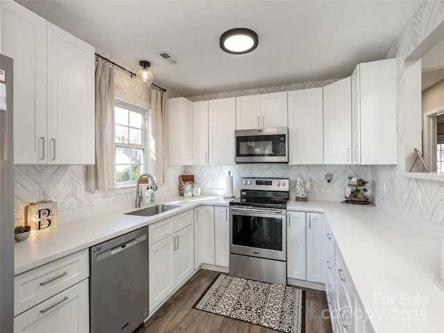 kitchen featuring backsplash, stainless steel appliances, sink, and white cabinets