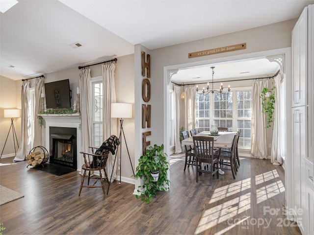 dining area with a fireplace with flush hearth, wood finished floors, visible vents, and baseboards