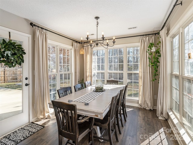 dining area featuring an inviting chandelier, visible vents, dark wood finished floors, and a textured ceiling