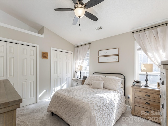 carpeted bedroom with multiple closets, ceiling fan, and lofted ceiling