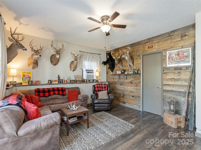 living room featuring ceiling fan, wooden walls, dark hardwood / wood-style flooring, and a textured ceiling