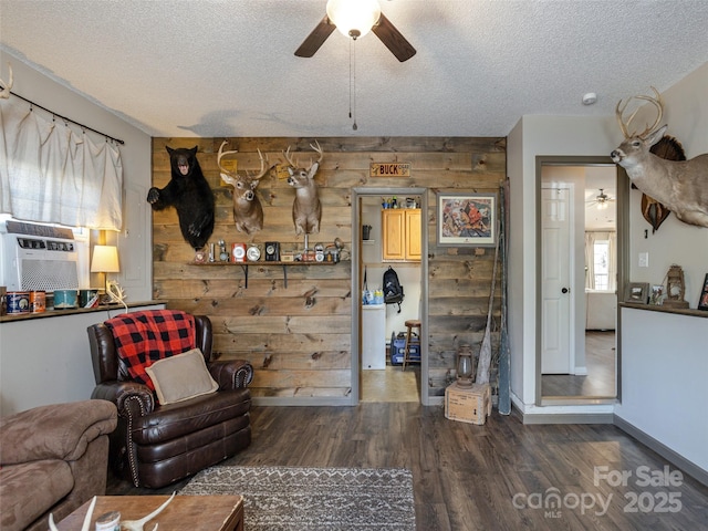 living room featuring ceiling fan, dark wood-type flooring, a textured ceiling, and wooden walls