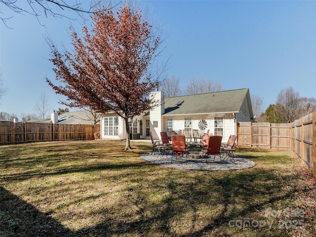 rear view of property with a patio, a lawn, a chimney, and a fenced backyard