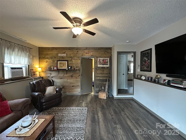 living area featuring cooling unit, dark wood-style flooring, wood walls, and a textured ceiling