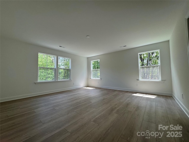 unfurnished room featuring dark wood-style floors, baseboards, and visible vents