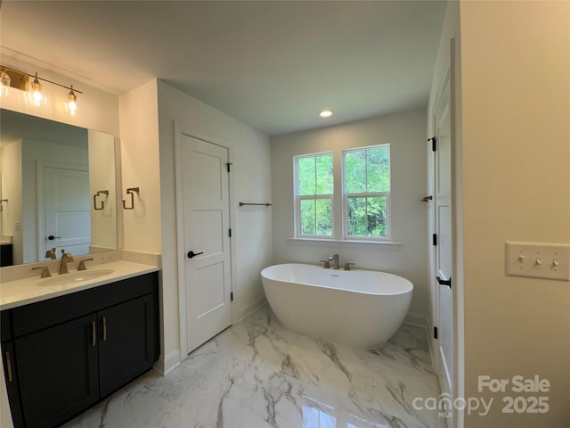 full bathroom featuring vanity, marble finish floor, a freestanding bath, baseboards, and recessed lighting