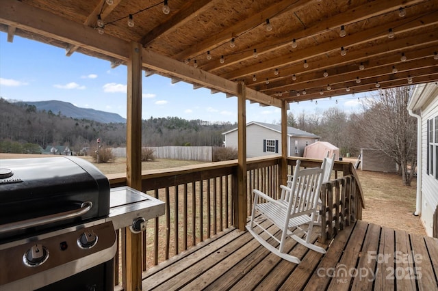 wooden terrace featuring a mountain view, grilling area, and a storage unit