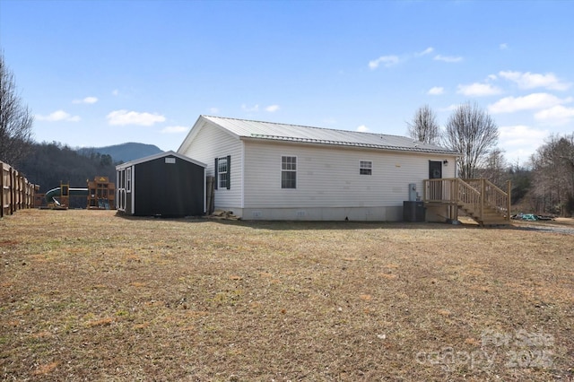 back of house with a storage shed, a yard, a mountain view, and central air condition unit