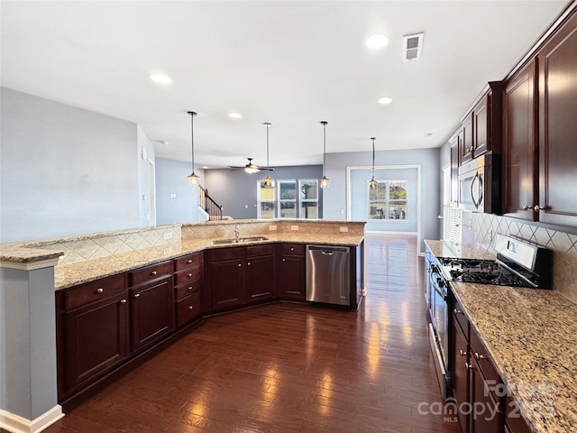 kitchen with sink, appliances with stainless steel finishes, hanging light fixtures, tasteful backsplash, and light stone countertops