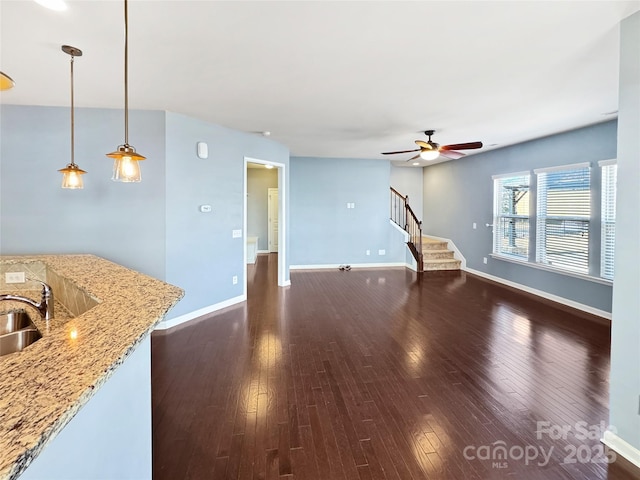 unfurnished living room featuring dark wood-type flooring, ceiling fan, and sink