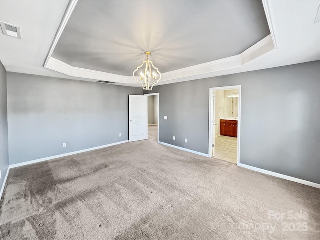 unfurnished room featuring light colored carpet, a tray ceiling, and a notable chandelier