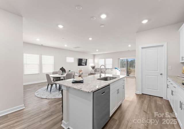 kitchen featuring white cabinetry, dishwasher, sink, light stone countertops, and a center island with sink