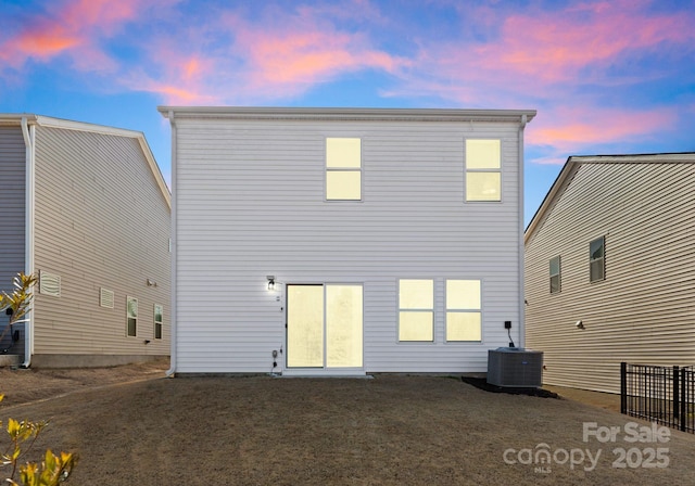 back house at dusk with a yard and central AC unit