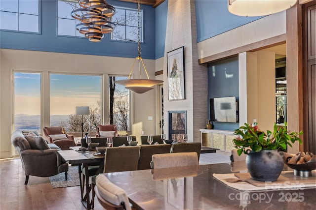 dining room featuring wood-type flooring, a towering ceiling, a wealth of natural light, and an inviting chandelier