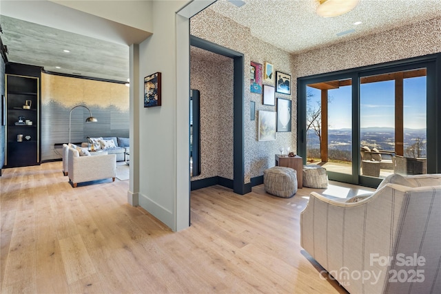 living room featuring wood finished floors, baseboards, and wallpapered walls