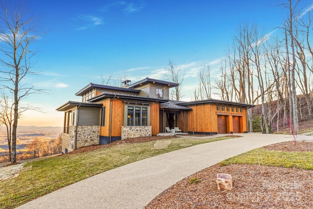 view of front of property with a garage, stone siding, and driveway