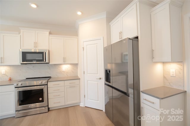 kitchen featuring crown molding, light hardwood / wood-style flooring, white cabinetry, stainless steel appliances, and tasteful backsplash