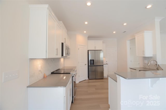 kitchen featuring sink, light hardwood / wood-style flooring, white cabinets, stainless steel appliances, and backsplash