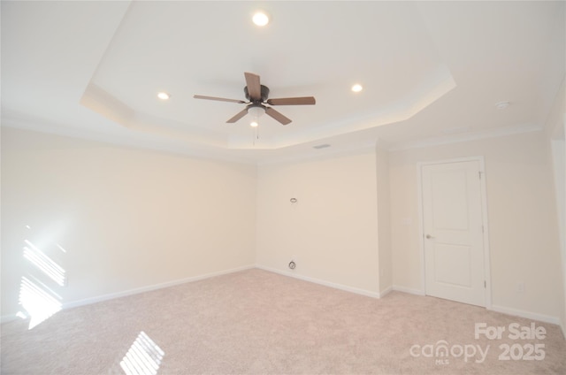 unfurnished room with ceiling fan, ornamental molding, a tray ceiling, and light carpet