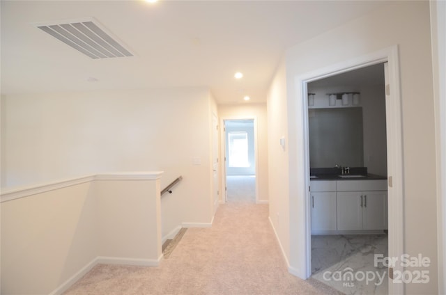 corridor featuring sink and light colored carpet